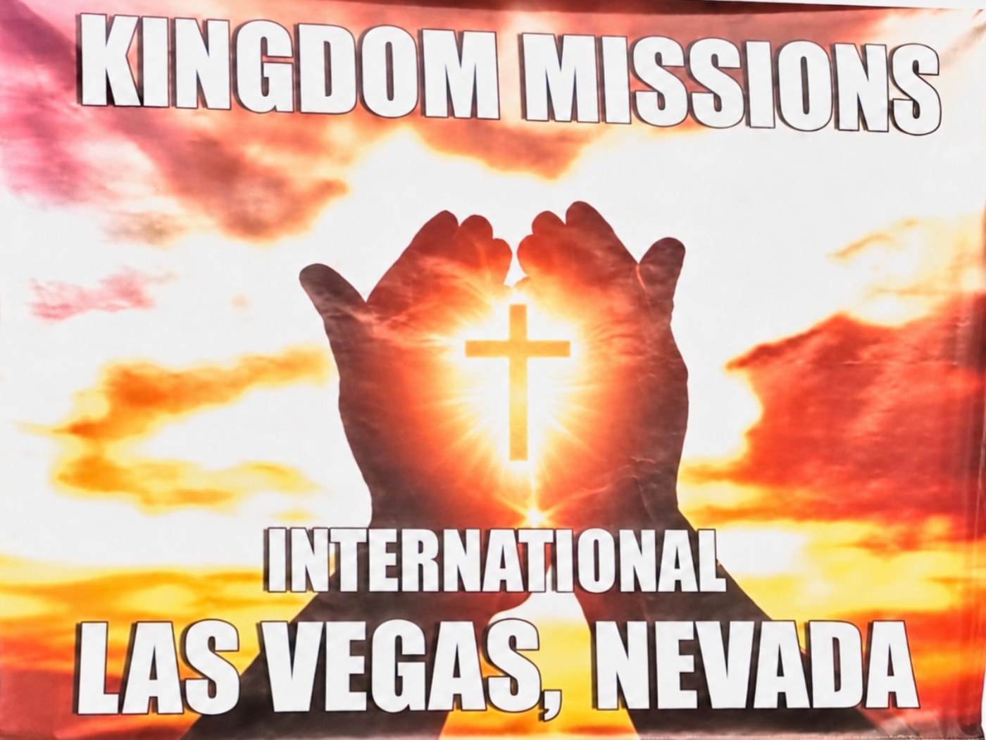 Kingdom Missions International banner showing raised hands surrounding a glowing cross against a sunset sky.
